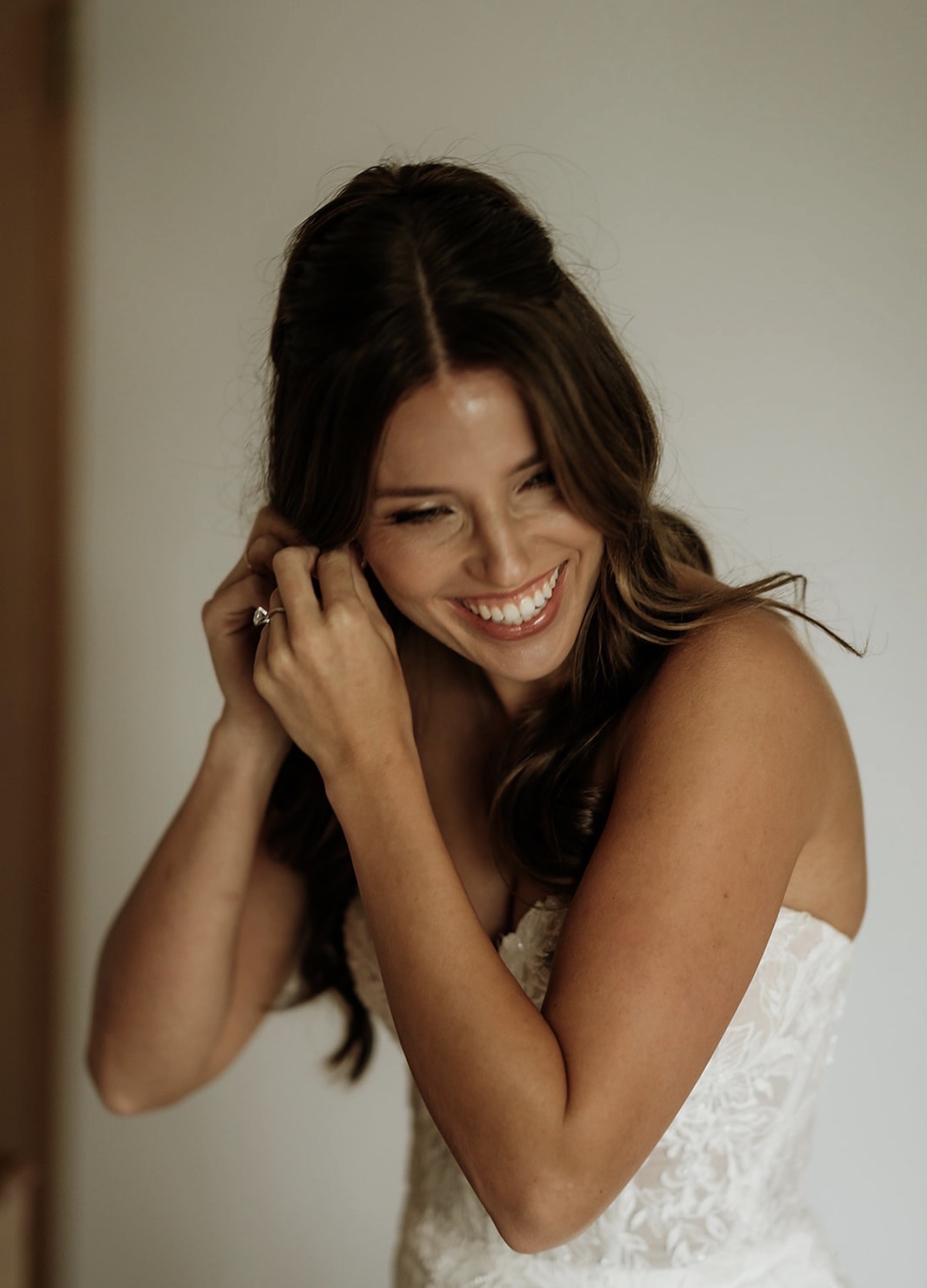 Bride smiling while adjusting her soft romantic hairstyle